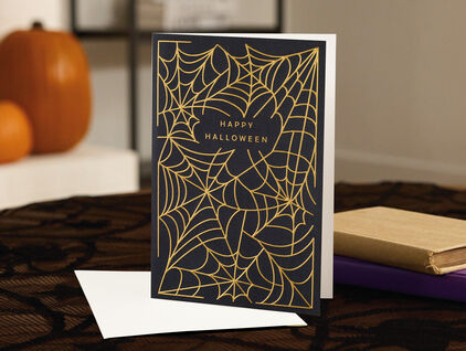 A black Halloween card featuring gold spiderwebs.